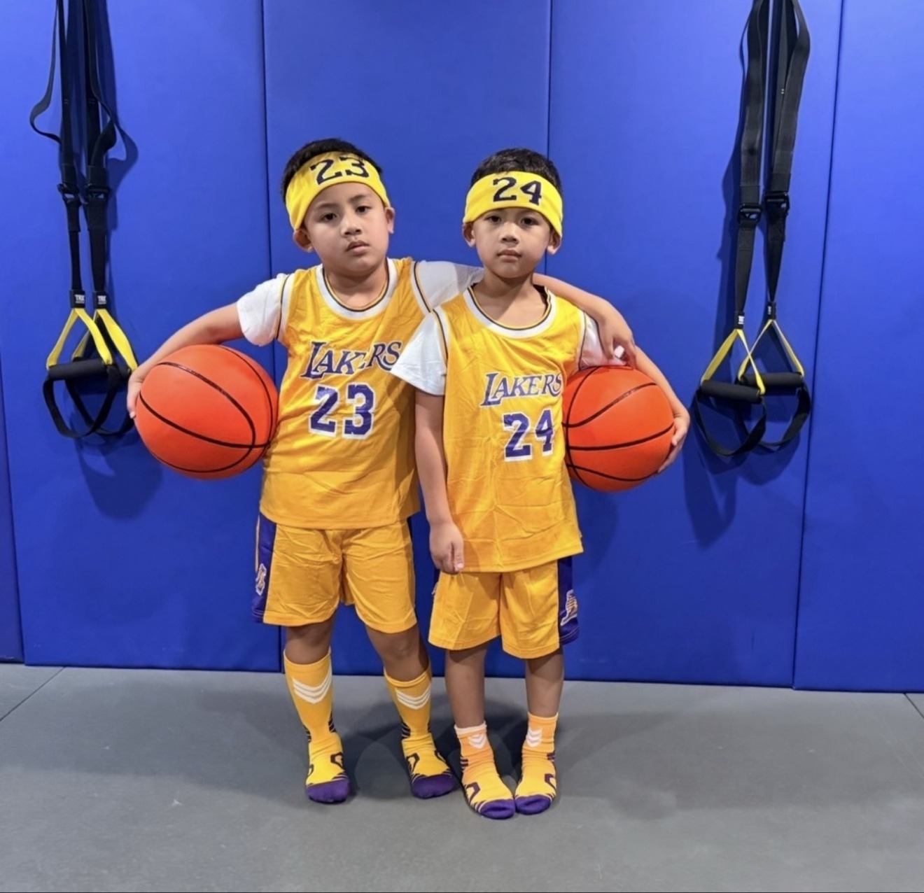 Two young athletes in gold Lakers jerseys holding basketballs during skills training