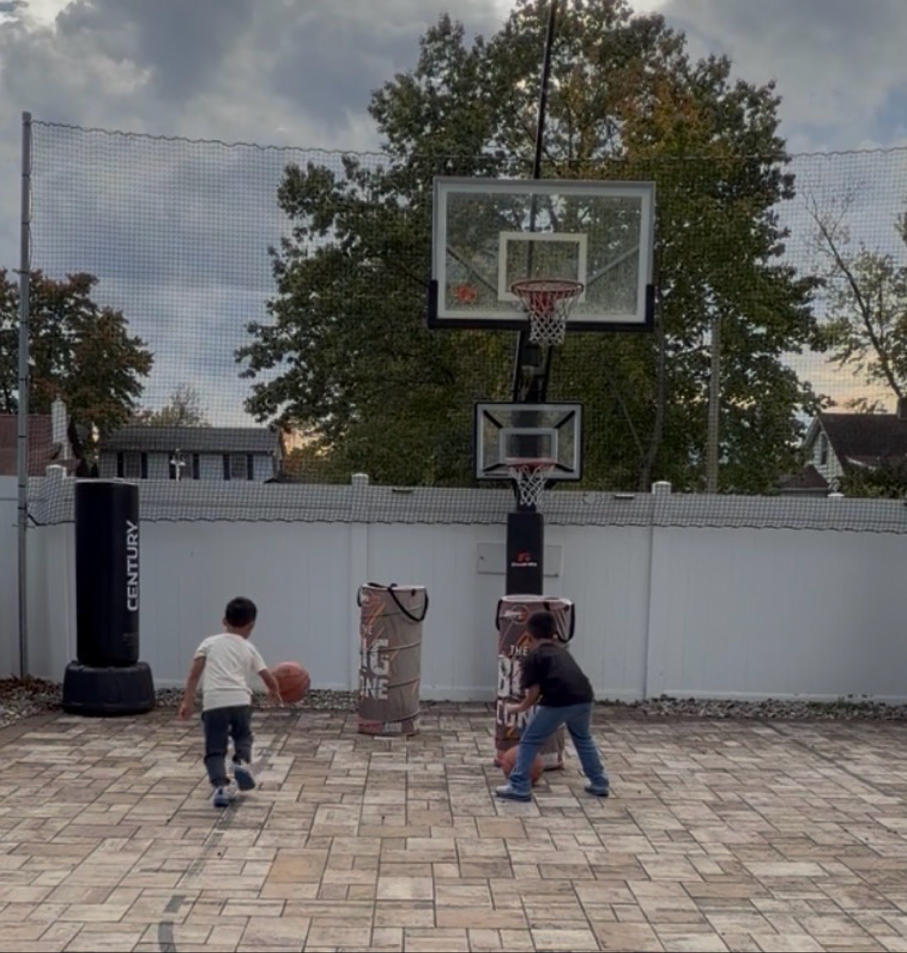 Two young basketball athletes practicing dribbling drills on a backyard court