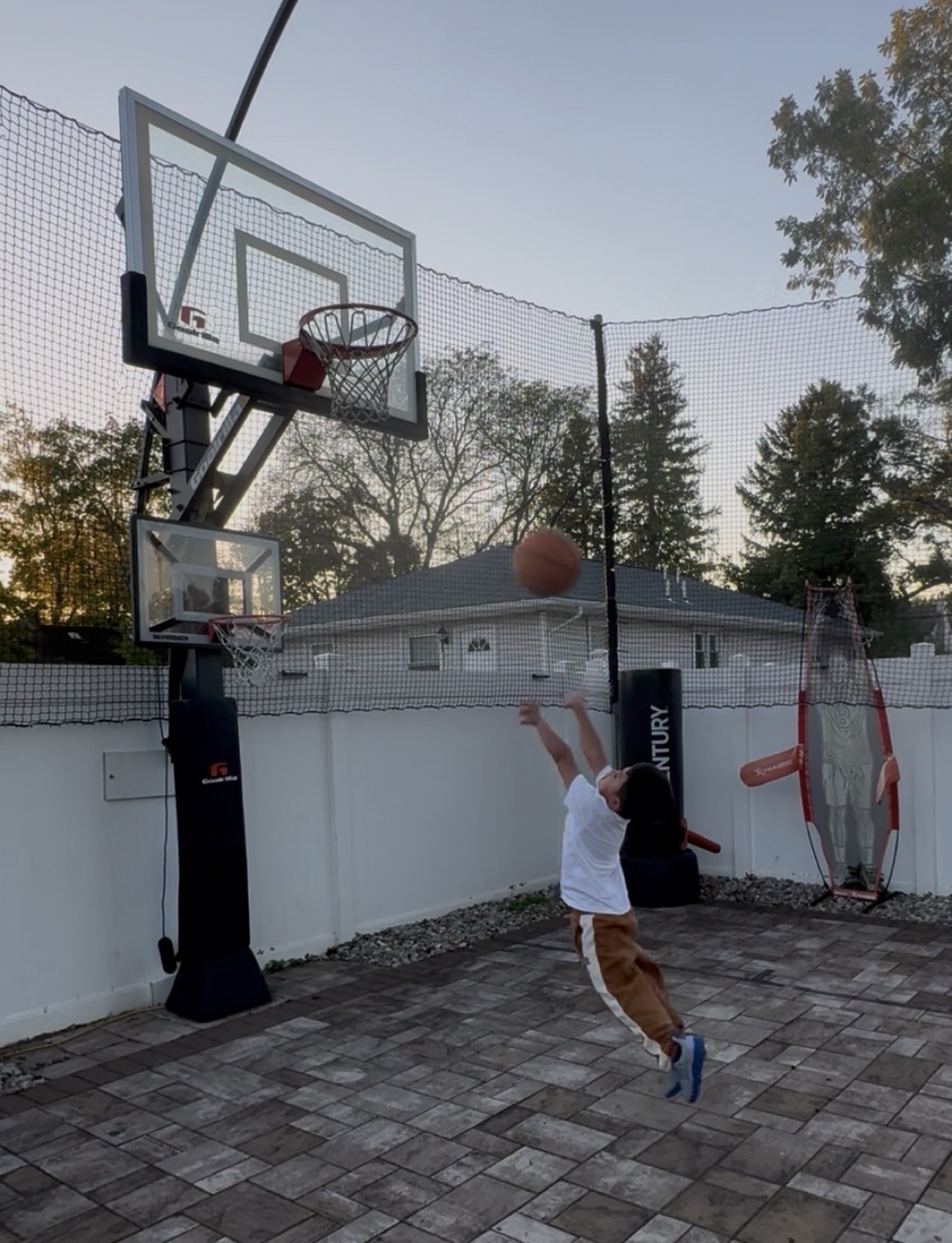 Young basketball athlete practicing a shot at an outdoor backyard hoop